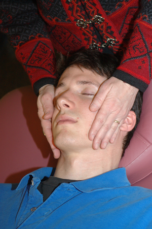 close up of a man's relaxed face as he receives reiki on his cheeks