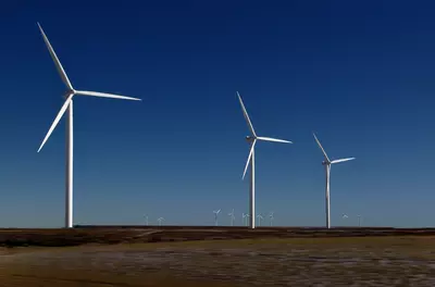 wind turbines on an empty field against a clear blue sky