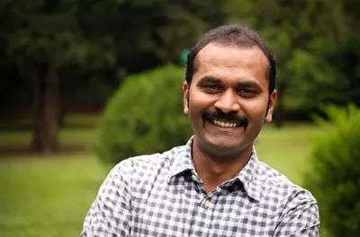 man with mustache standing outside and smiling at the camera