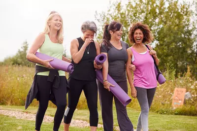 Group Of Mature Friends On Outdoor Yoga Retreat Walking Along Path