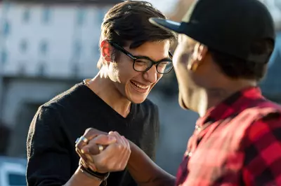 two friends smiling holding hands