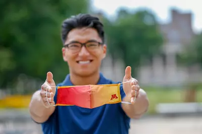 U of MN student holding mask