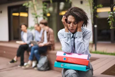 African American woman sitting away from peers looking stressed