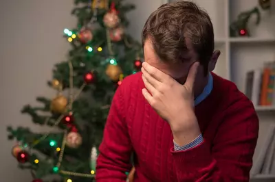 person holding their head in their hands in a red sweater