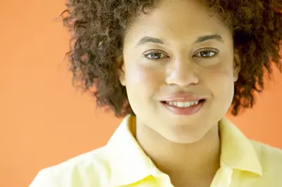 person smiling at the camera in a yellow button up.