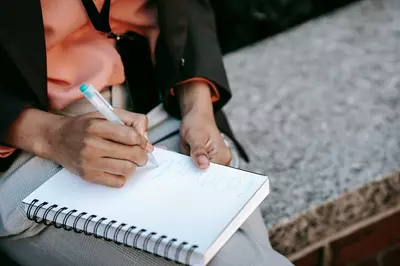 Person creating a to-be list instead of New Year's resolutions. The person is holding a white notepad.