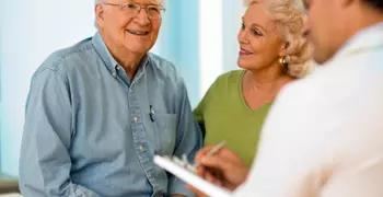 elderly couple speaking with a healthcare provider