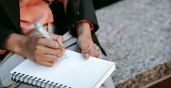 Person creating a to-be list instead of New Year's resolutions. The person is holding a white notepad.