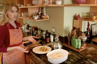 Woman standing in a kitchen next to a plate of cooked fish.