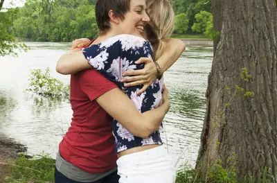 two friends hugging by a river