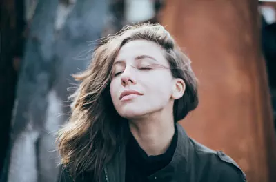 woman outside with her eyes closed, feeling the breeze